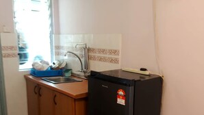 A compact kitchen with a sink, a black refrigerator, wooden cabinets, and a window with a view. - Glory by Alpine (Port Dickson)