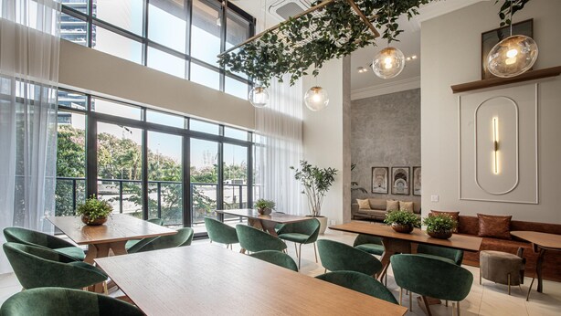 A modern dining area with large windows, green upholstered chairs, and a wooden table. - Vila Olimpia Viva Benx Flats by Feel Sampa (São Paulo)