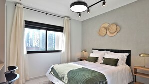 A modern bedroom with a large bed, a bedside table with a lamp, a window with curtains, and a city view. - Vila Olimpia Viva Benx Flats by Feel Sampa (São Paulo)