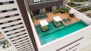 A rooftop pool with lounge chairs and a table, surrounded by a modern building with large windows. - Vila Olimpia Viva Benx Flats by Feel Sampa (São Paulo)