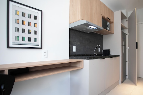 A modern kitchen with wooden cabinets, a black countertop, and a microwave.