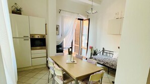 A compact kitchen with white cabinets, a built-in oven, and a dining area with a wooden table and four chairs.