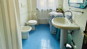 A bathroom with a toilet, bidet, sink, and a mirror.