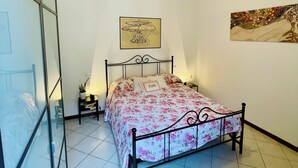 A bedroom with a bed, a bedside table, a lamp, and a ceiling light.