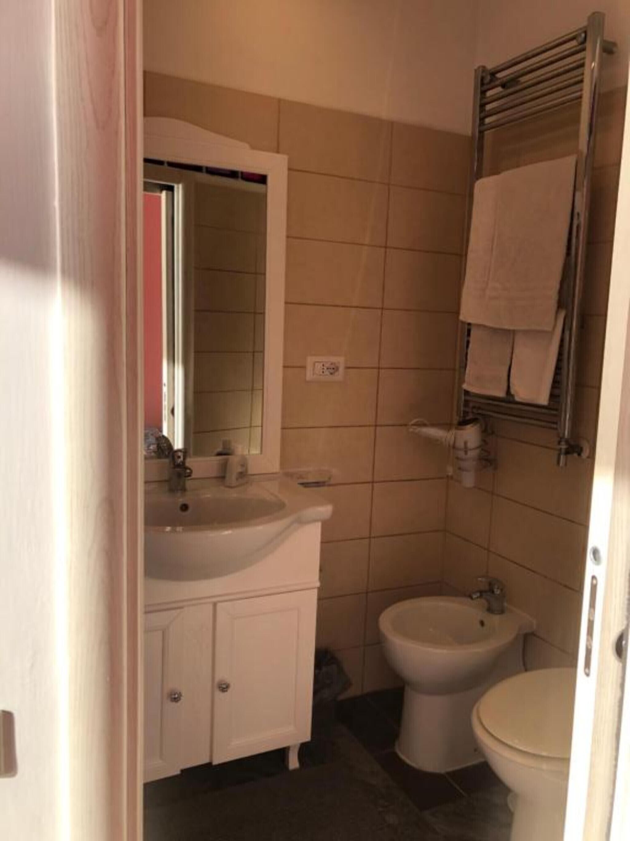 Een badkamer met een wastafel, spiegel, toilet en handdoekhouder.