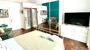 Habitación de hotel con cama, televisor, escritorio y armario.