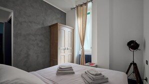 A hotel room with a bed, a wardrobe, a desk with a lamp, and a window with curtains. - City Center Suite (Milan)