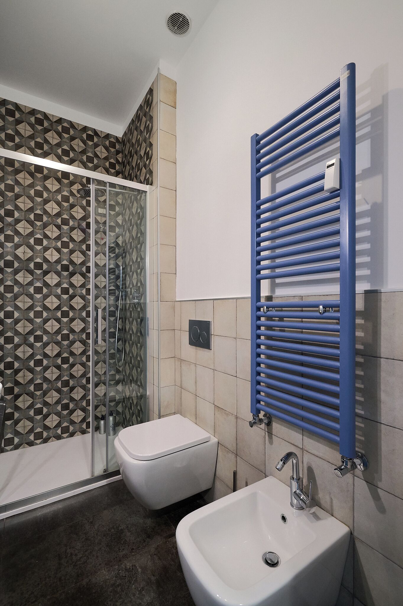 Une salle de bain avec une douche à parois de verre, des toilettes blanches et un lavabo doté d’un porte-serviettes bleu.