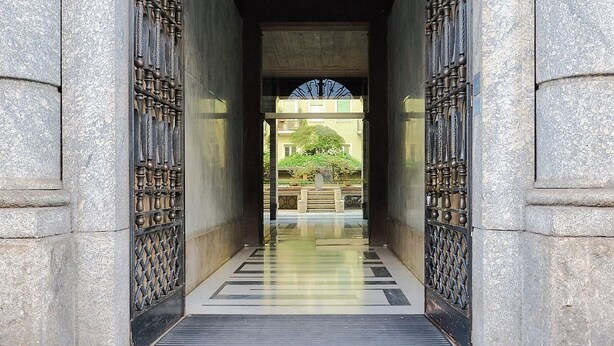 A stone archway with intricate metalwork, leading to a covered walkway. - City Center Suite (Milan)
