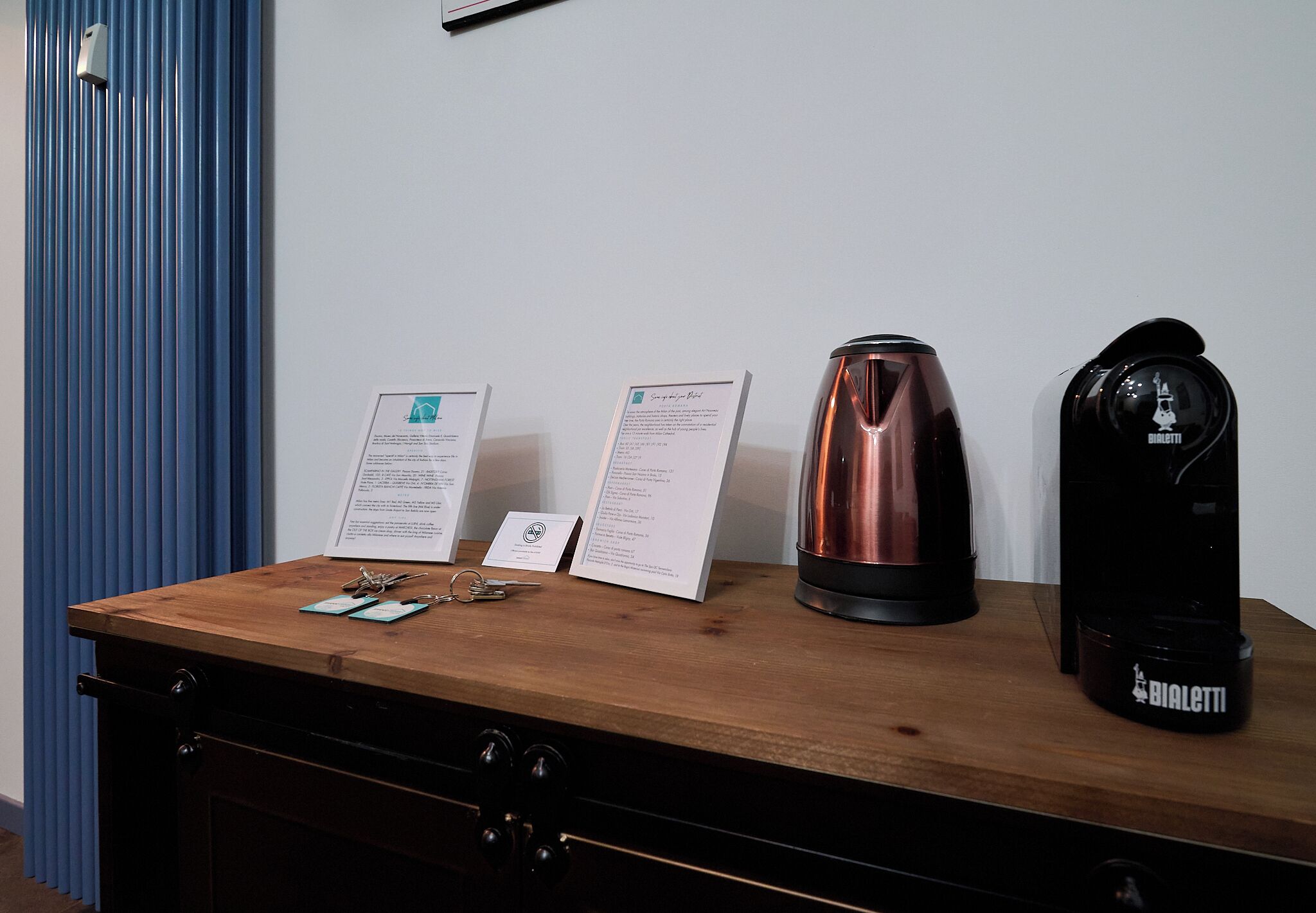 Ein Holztisch mit einer schwarzen Kaffeemaschine, einem kupferfarbenen Wasserkocher und zwei Informationskärtchen.