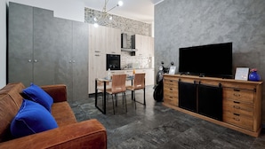 A modern living room with a brown leather sofa, a wooden cabinet with drawers, and a television. - City Center Suite (Milan)
