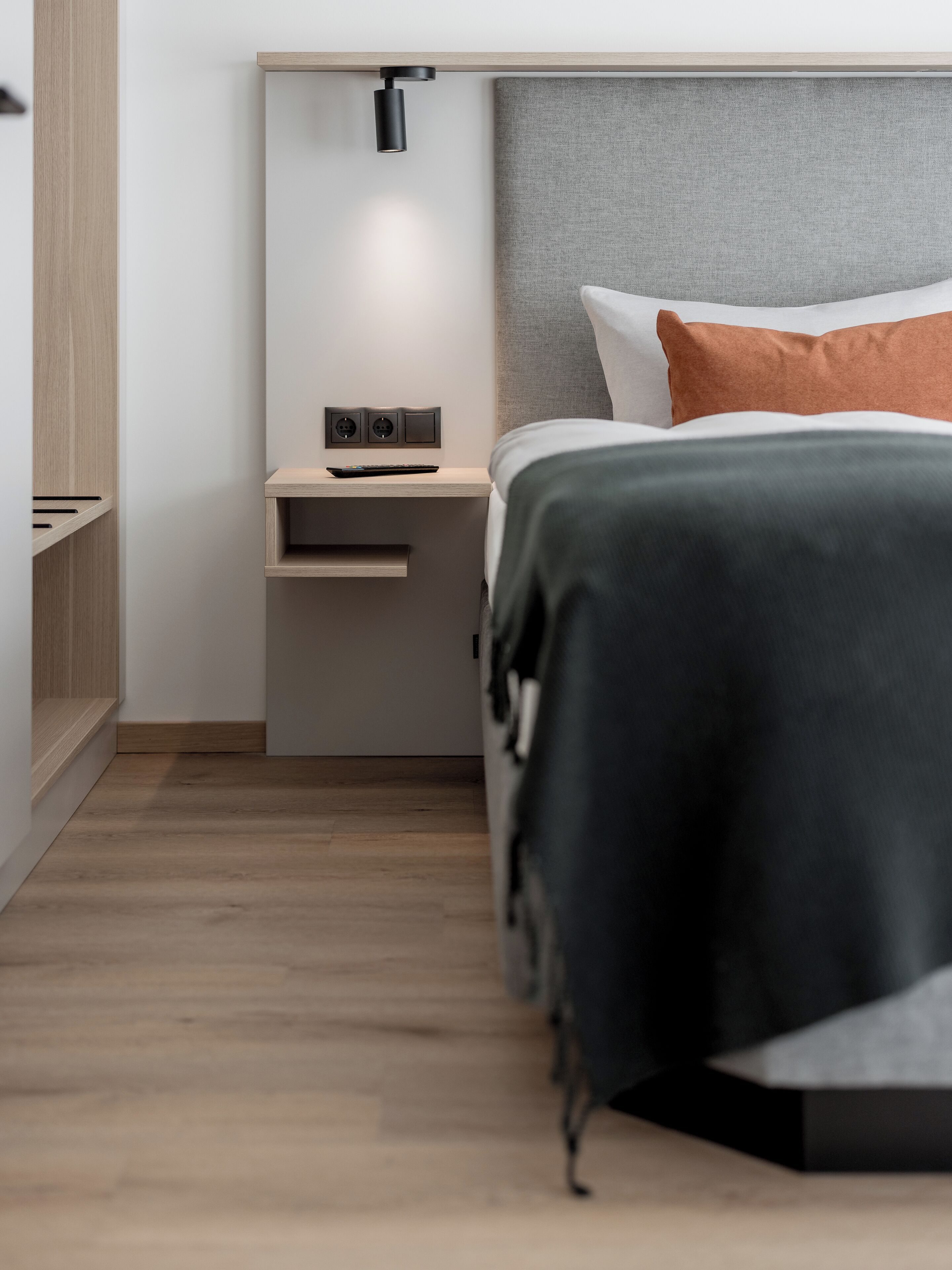 Ein modernes Schlafzimmer mit Bett, Nachttisch und Wandleuchte.