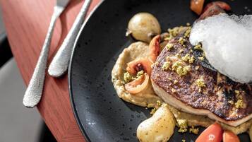 A plate with a steak, potatoes, and vegetables on a dark plate.
