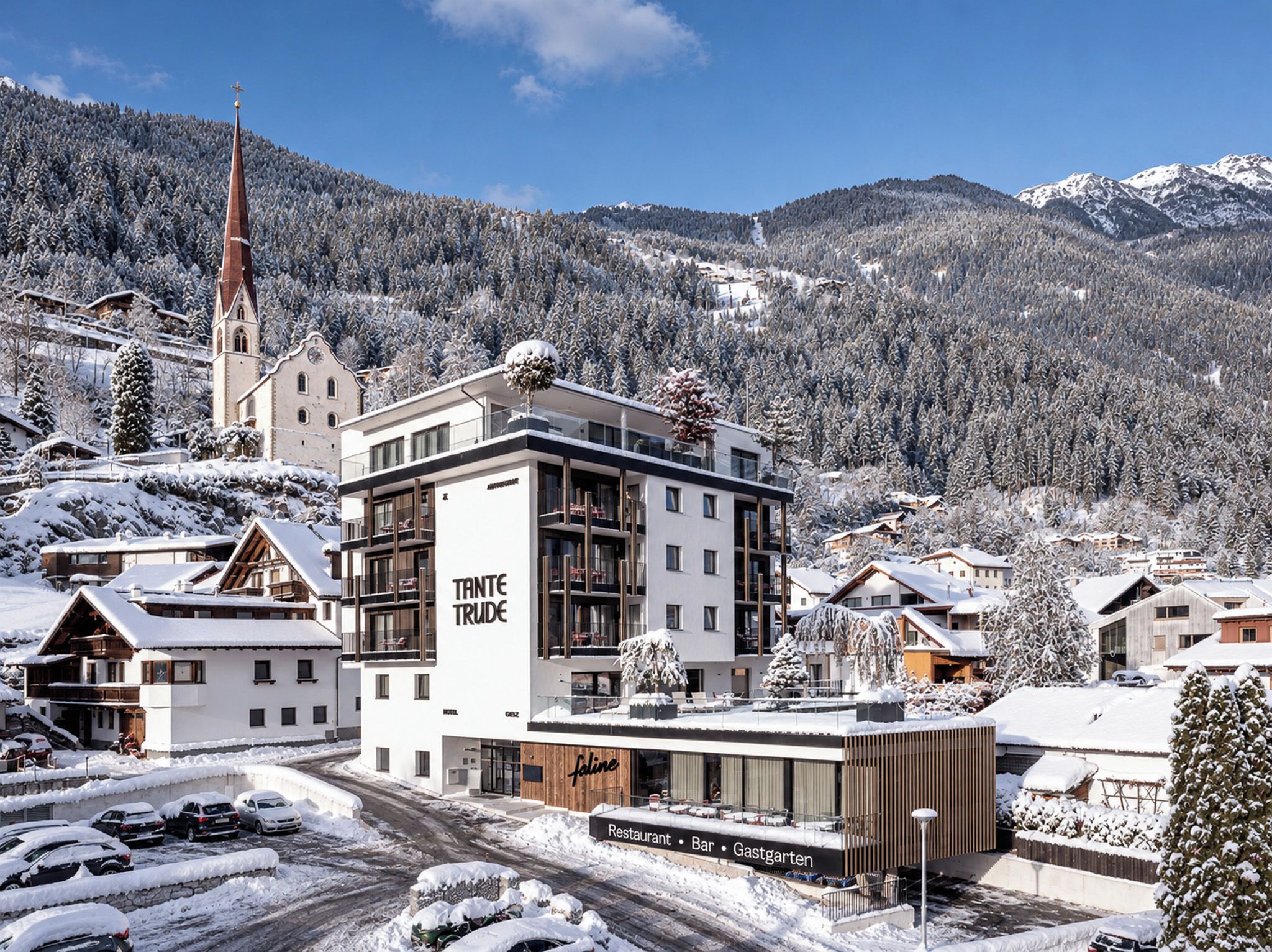 Un hotel moderno con restaurante, bar y jardín gastronómico, rodeado de edificios nevados y montañas.