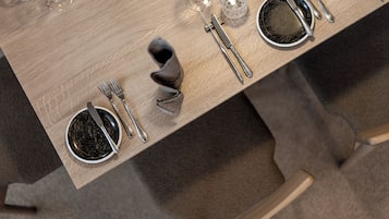 Una mesa de comedor con cubiertos y vasos, lista para una comida.