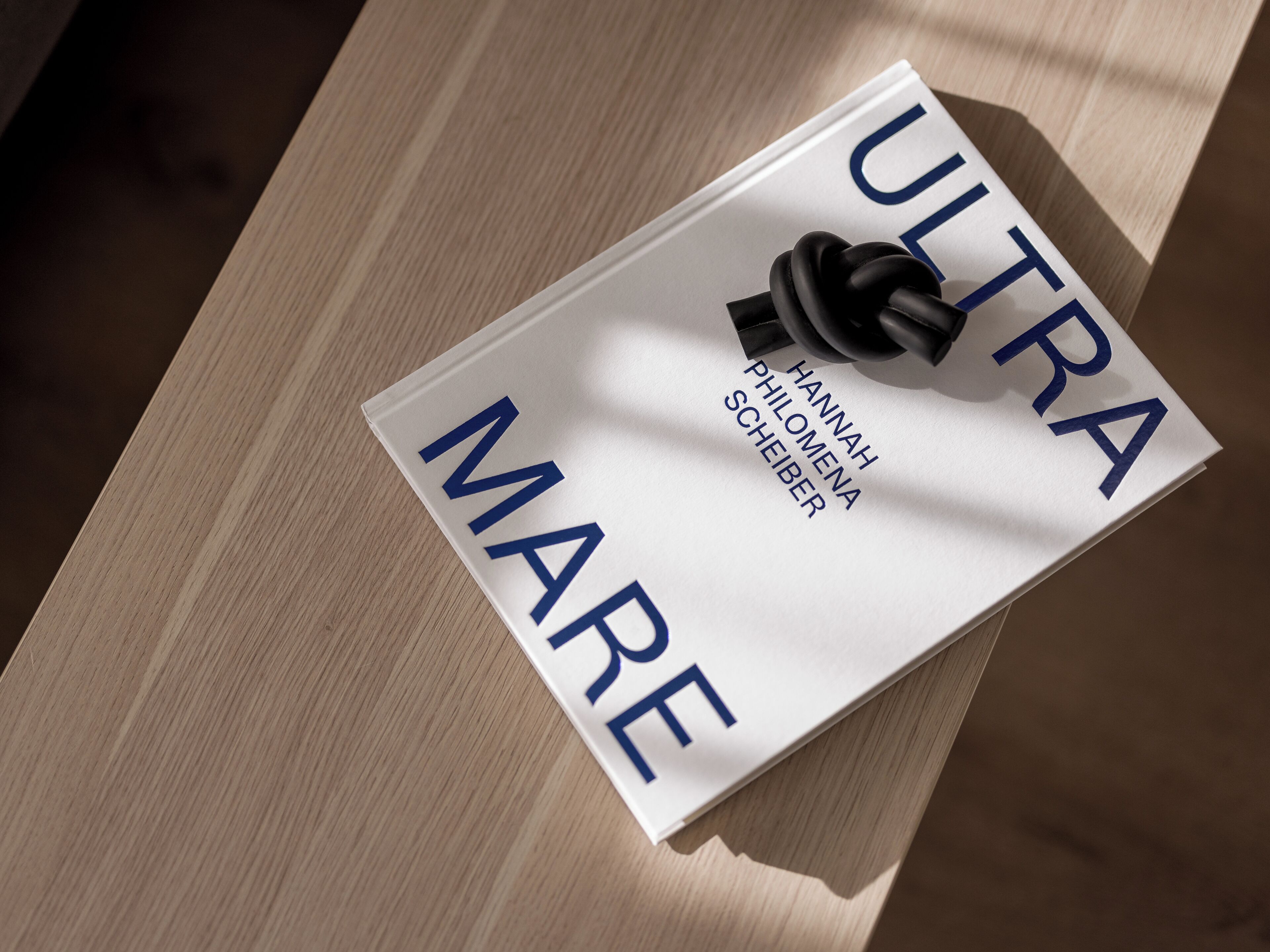 Ein Buch mit dem Titel „ULTRA MARE“ von Hannah Phillomena Scheiber auf einer Holztischfläche.