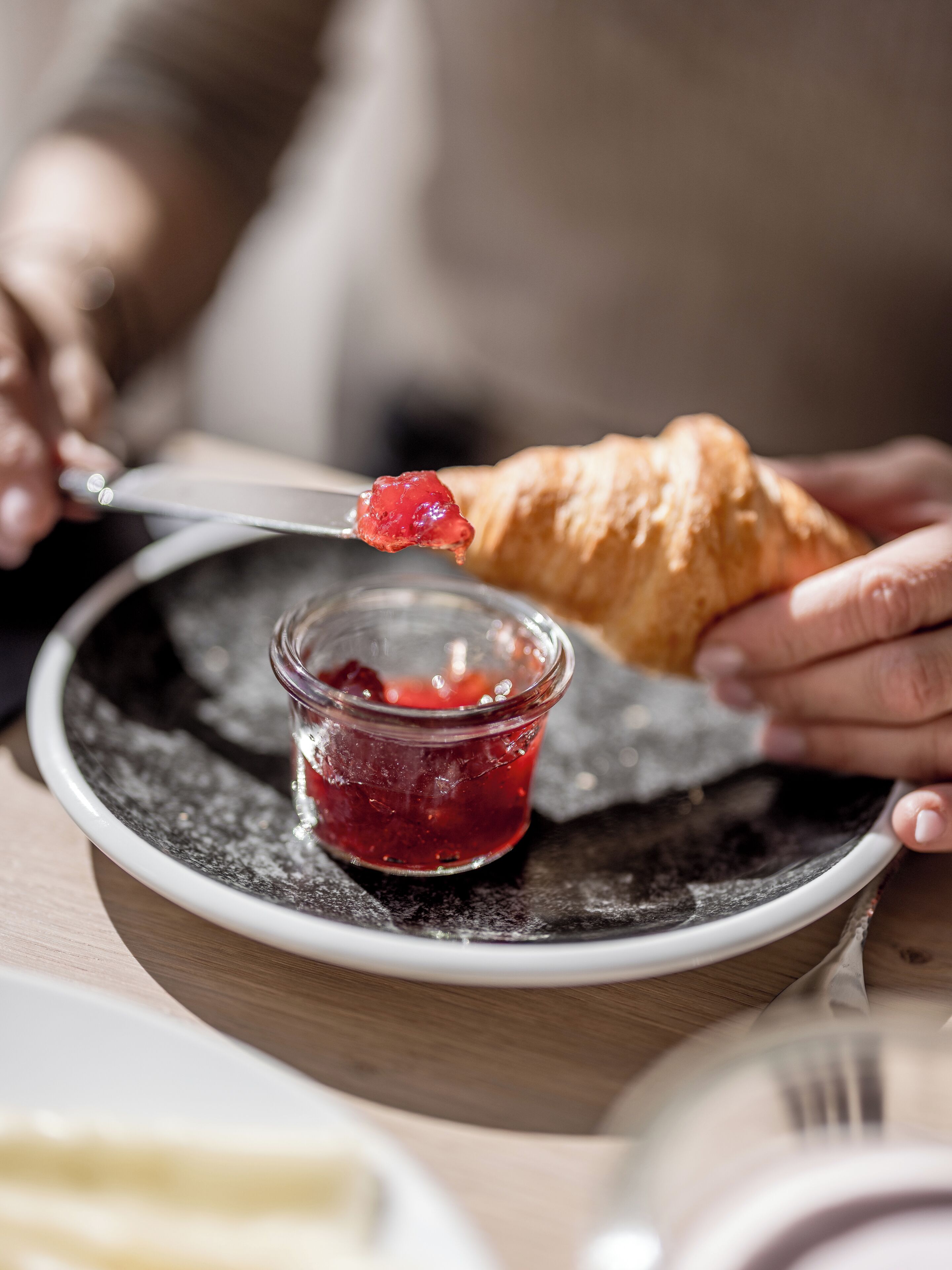 Iemand belegt een croissant met jam.