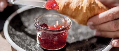 Iemand belegt een croissant met jam.