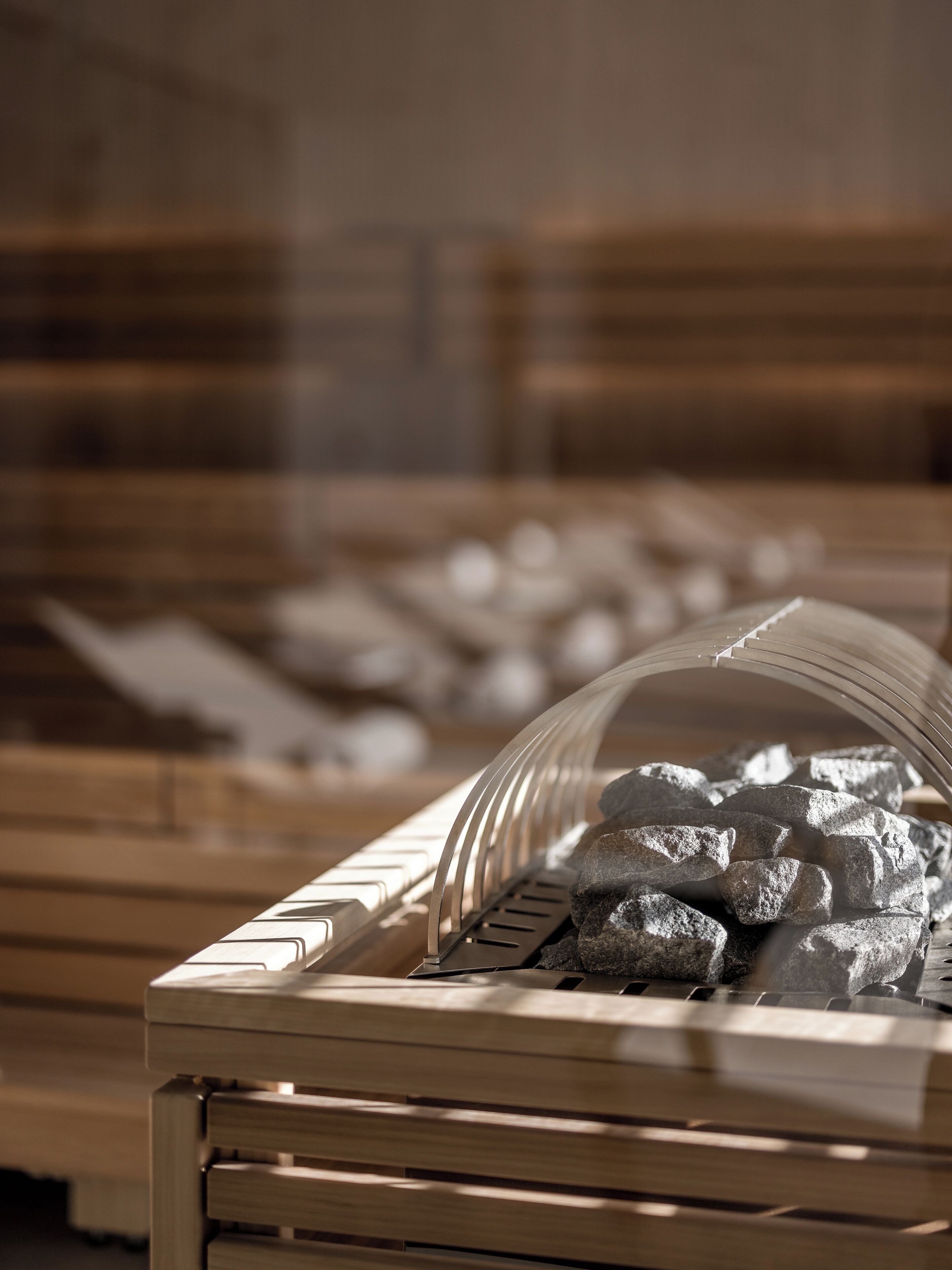 Eine hölzerne Bank mit runder Glasplatte, umgeben von Steinen und einem Metallgeländer.