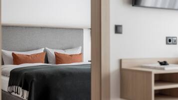 Un dormitorio moderno con una cama, una mesita de noche y un televisor montado en la pared.