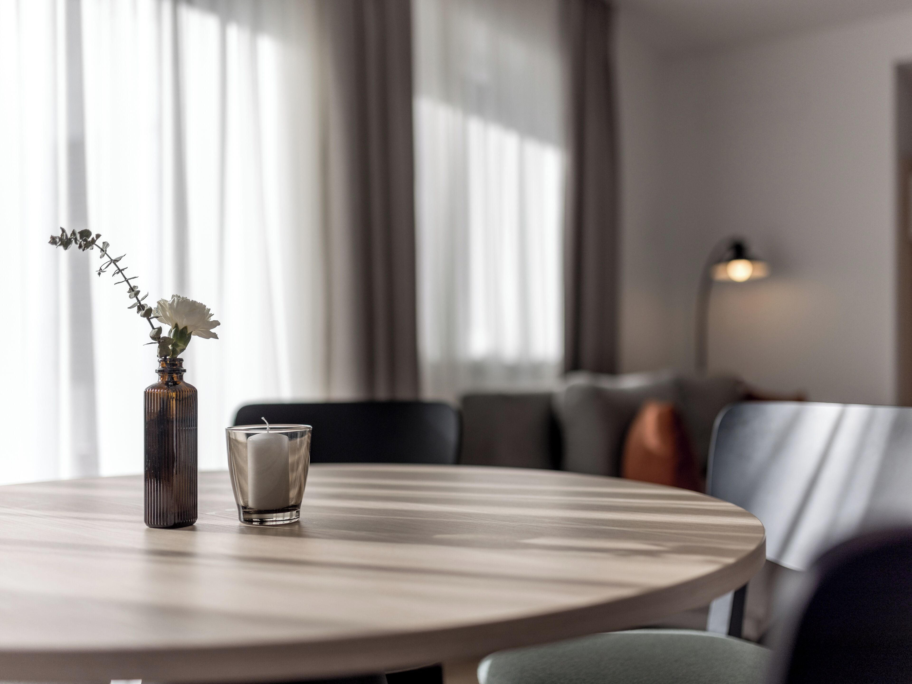 Een ronde tafel met een bloevas en een kaars.