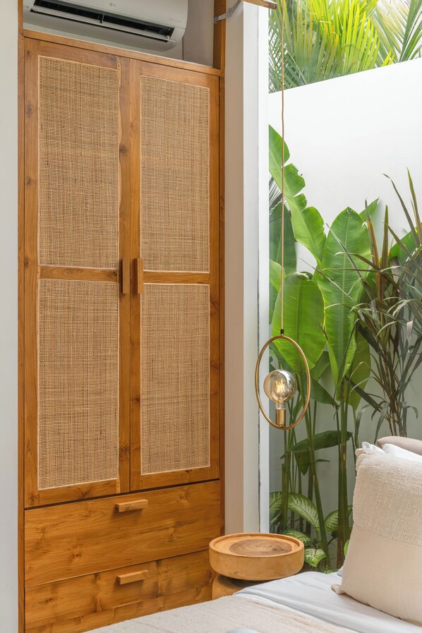 Une pièce avec une armoire en bois, un lit avec un oreiller blanc et un luminaire suspendu.