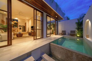 Une maison moderne dotée d’une piscine, de grandes portes-fenêtres coulissantes et d’un intérieur chaleureux aménagé avec du mobilier.