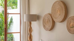 A modern living room with a beige sofa, a round wooden coffee table, a floor lamp, and three woven wall decorations. - Villa Inka (Canggu)