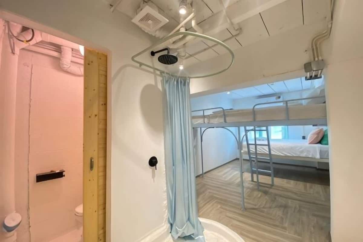 Una habitación con literas, zona de ducha y baño a la vista.