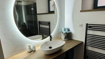A modern bathroom with a round mirror, a sink, and a towel rack.