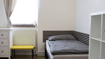 Une chambre à coucher avec un lit, un bureau, une chaise et un radiateur.