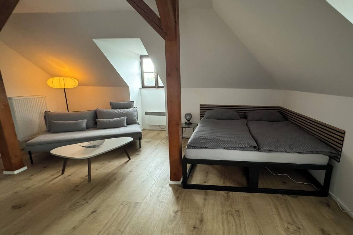 A cozy loft bedroom with a bed, a sofa, and a small table.
