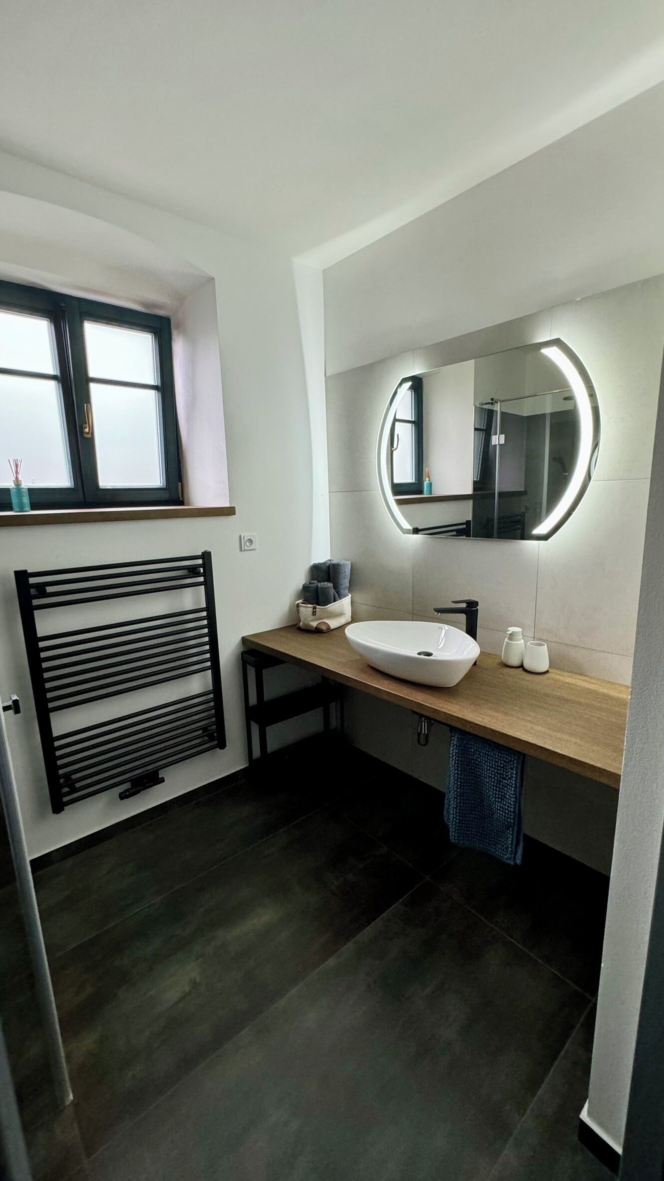 Un baño moderno con un espejo grande, un lavabo sobre encimera y un perchero para toallas.