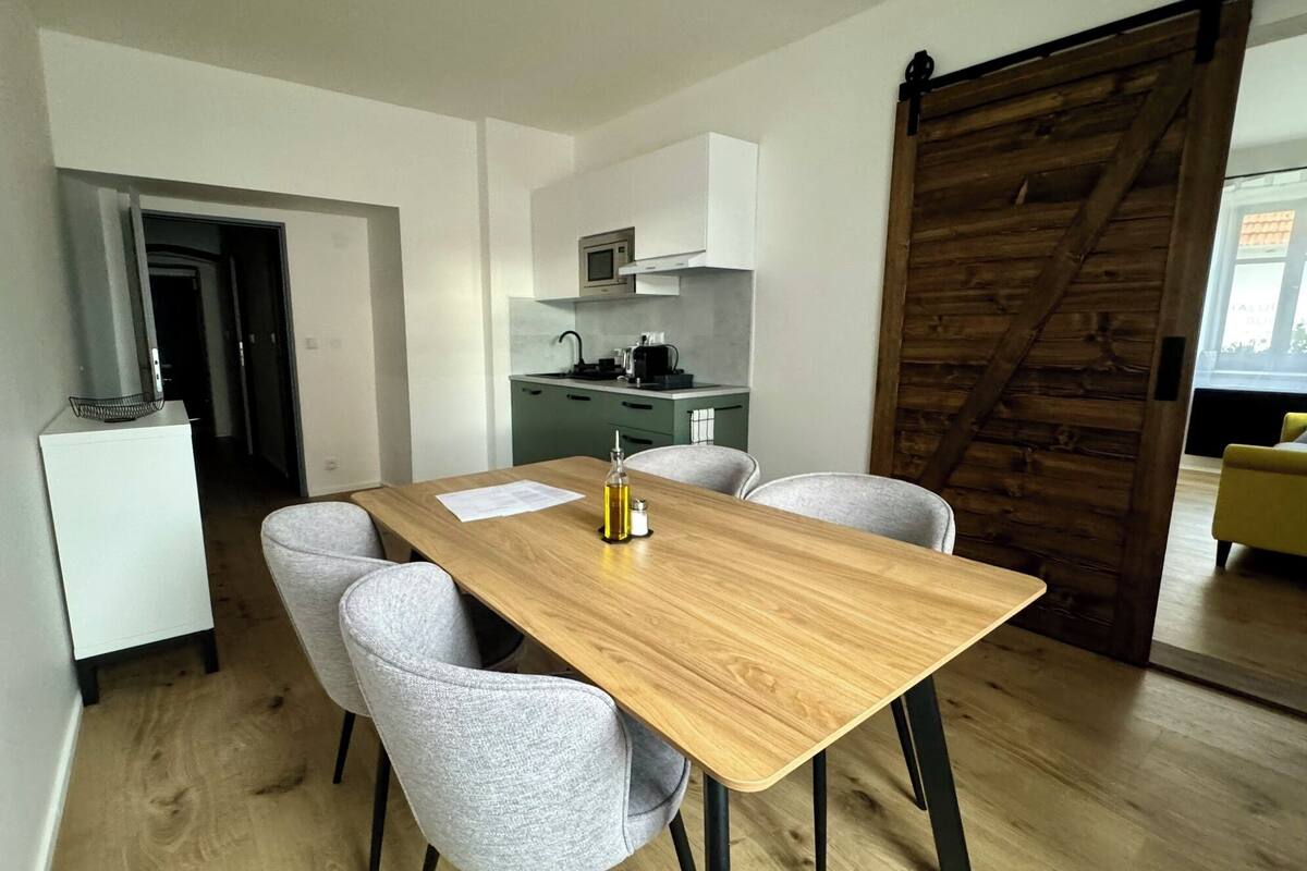 A compact living space with a dining area, kitchenette, and a sliding door leading to another room.