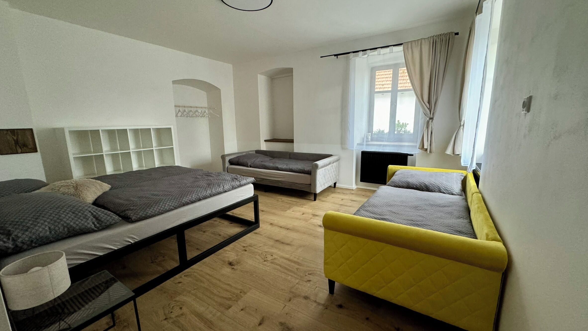 Une chambre à coucher moderne et bien éclairée, avec un lit, un canapé et une petite table.