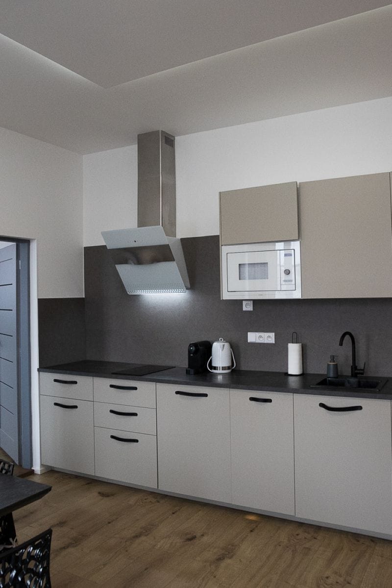 A modern kitchen with a microwave, kettle, and kettle stand on the countertop.