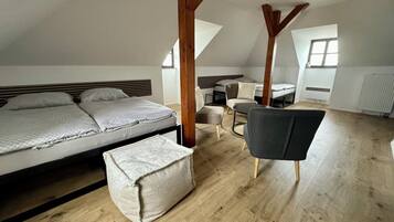 A bedroom with a large bed, a small sofa, a chair, and a wooden ceiling structure.