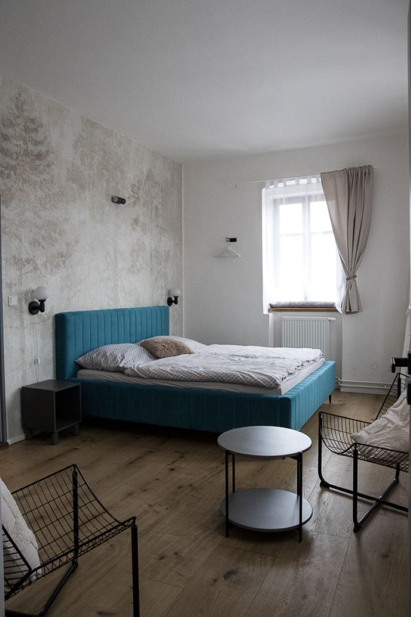 Un dormitorio con una cama, mesitas de noche, una mesa redonda y una silla.