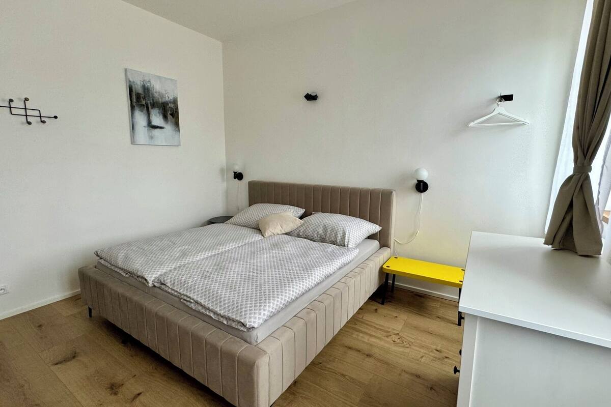 A bedroom with a bed, bedside table, and a small desk.
