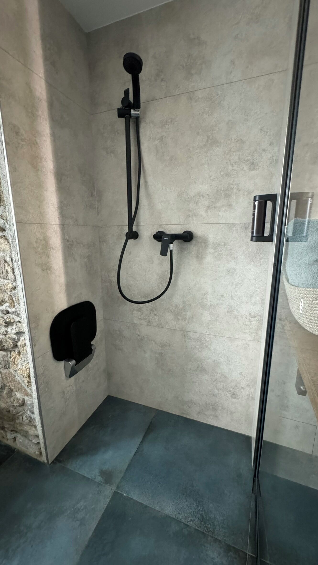 Un baño moderno con cabina de ducha, un perchero para toallas y puerta de cristal para la ducha.