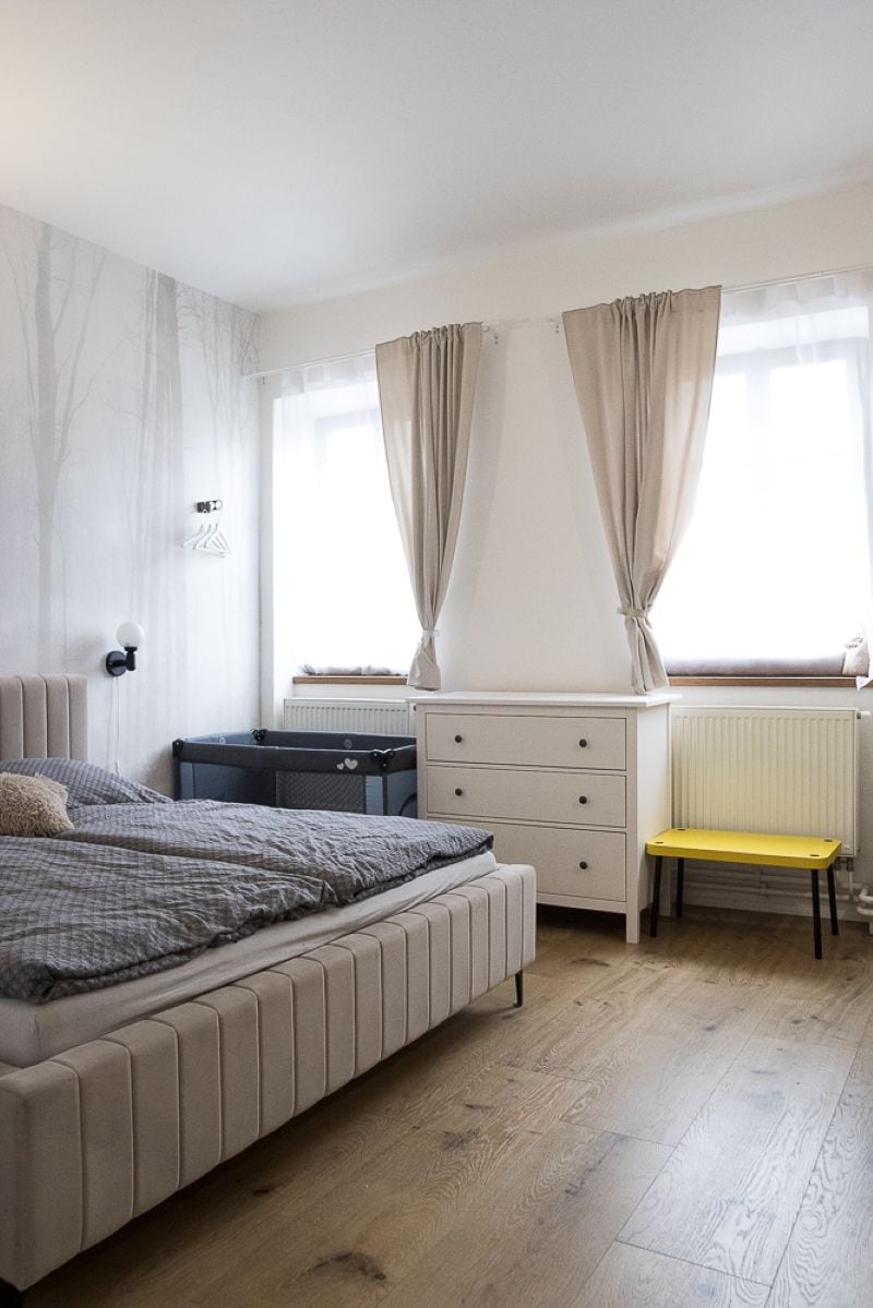 A bedroom with a bed, a dresser, a chair, and a window with curtains.