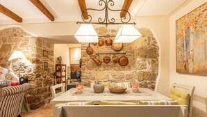 A dining area with a stone wall, a chandelier, and a table set for two. - Apartment 'La Terrazza, Cetona, Toscana' with Mountain View, Wi-Fi and Air Conditioning (Cetona)