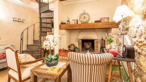A cozy living room with a fireplace, a wooden staircase, and a striped armchair. - Apartment 'La Terrazza, Cetona, Toscana' with Mountain View, Wi-Fi and Air Conditioning (Cetona)