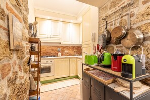 A kitchen with stone walls, wooden cabinets, and various appliances including a coffee maker, toaster, and kettle. - Apartment 'La Terrazza, Cetona, Toscana' with Mountain View, Wi-Fi and Air Conditioning (Cetona)