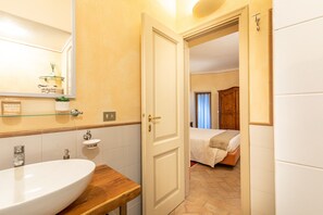 A bathroom with a large sink, a mirror, and a door leading to a bedroom with a bed and wooden furniture. - Apartment 'La Terrazza, Cetona, Toscana' with Mountain View, Wi-Fi and Air Conditioning (Cetona)