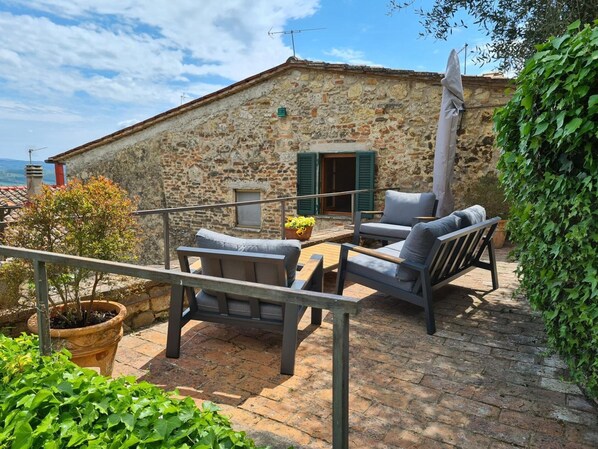A stone building with a balcony, outdoor seating, and greenery. - Apartment 'La Terrazza, Cetona, Toscana' with Mountain View, Wi-Fi and Air Conditioning (Cetona)