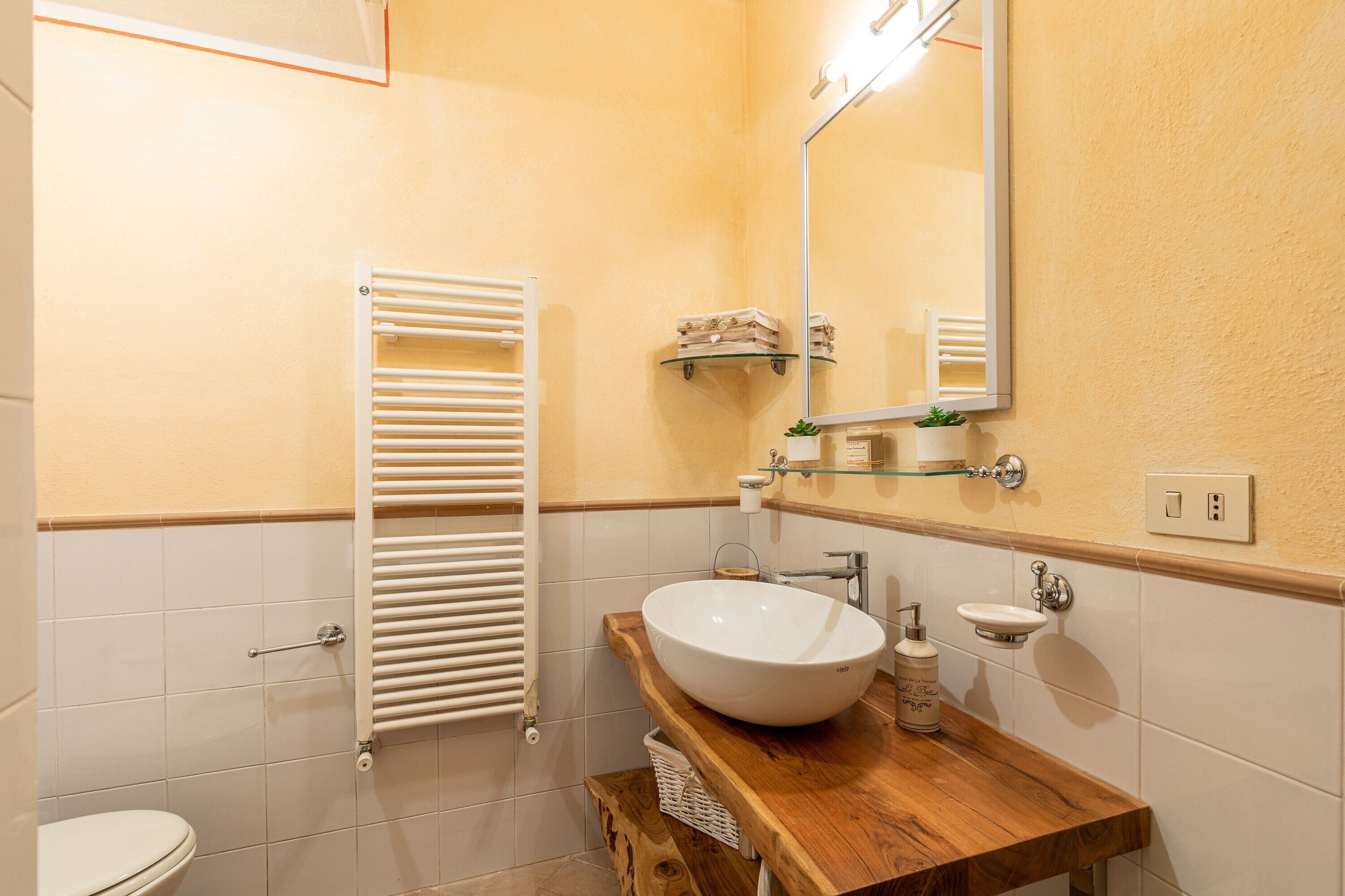 A bathroom with a wooden vanity, a white sink, a towel rack, and a mirror.