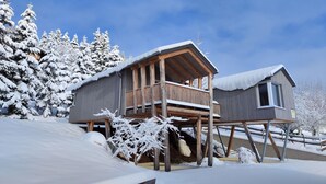 En træhytte med balkon, omgivet af sneklædte træer.