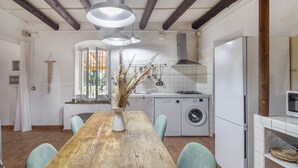 A kitchen with a wooden table, washing machine, and a microwave.