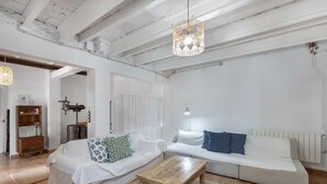 A spacious living room with a white sofa, a wooden coffee table, and a hanging light fixture.